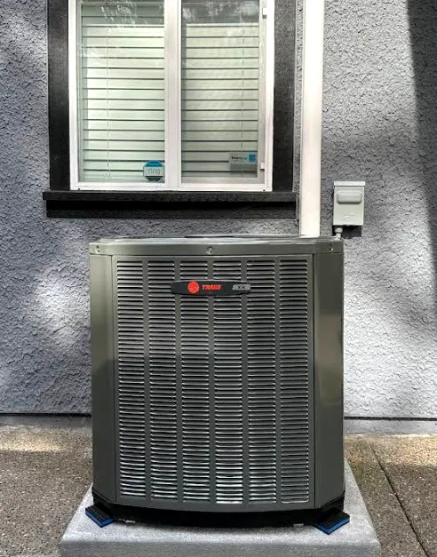 Trane XR unit on a clean concrete pad below a window