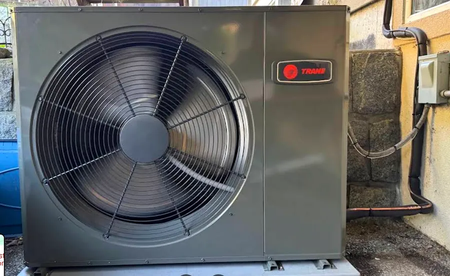 Low-profile Trane unit fitted into a tight space beside a stone wall
